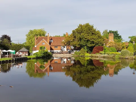 The Mill House in North Warnborough reflected in its millpond, surrounded by trees